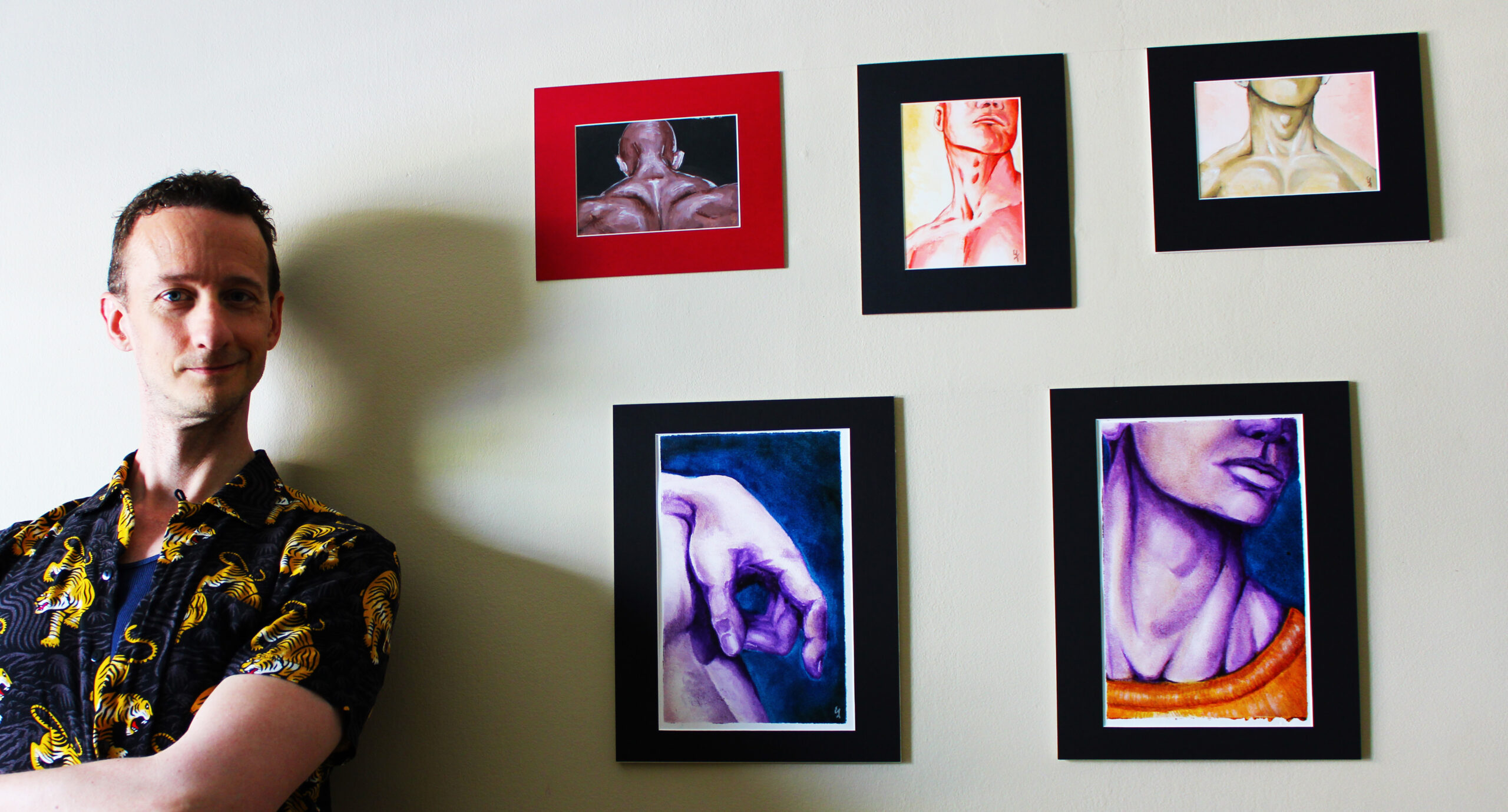 artist Edward Ficklin leaning against a wall displaying a set of five small paintings