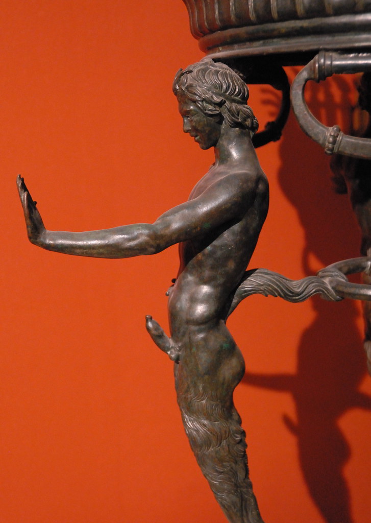 close up of the leg of a bronze tripod excavated at pompeii in the shape of a muscular young man with prominent erection and outstretched hand