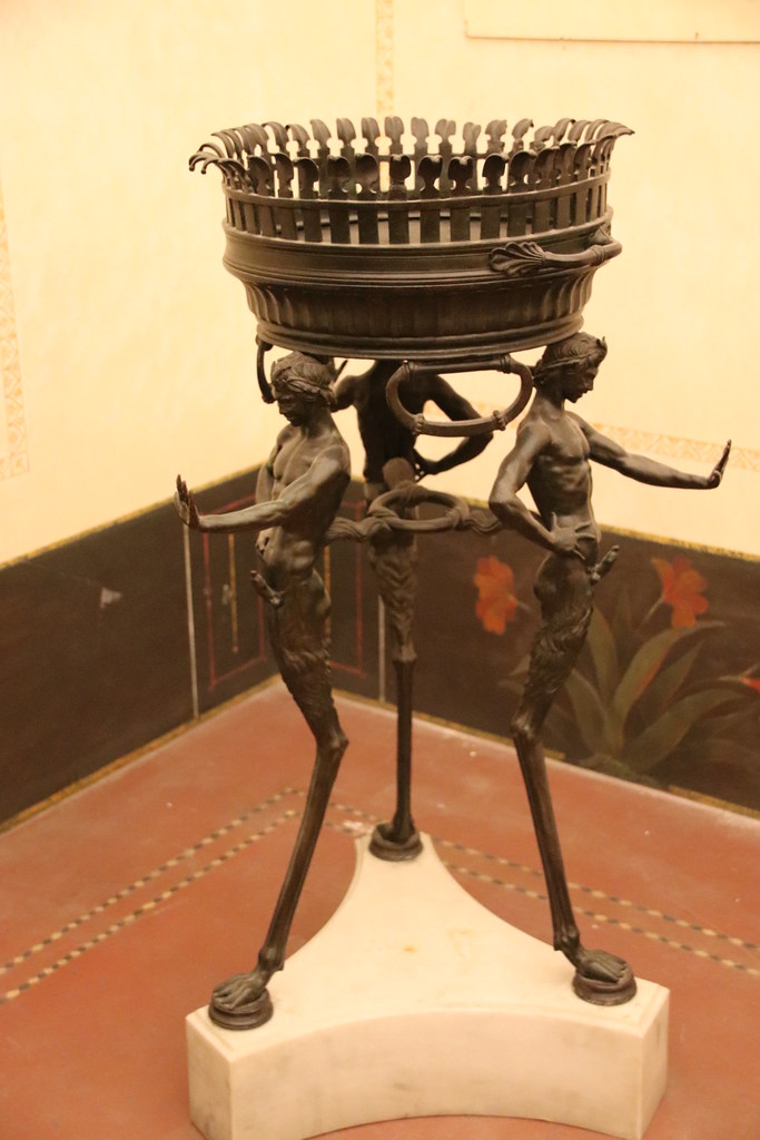 bronze tripod unearthed at pompeii's house of the vettii. the legs are int he shape of muscular youths with prominent erections and an outstretched hand