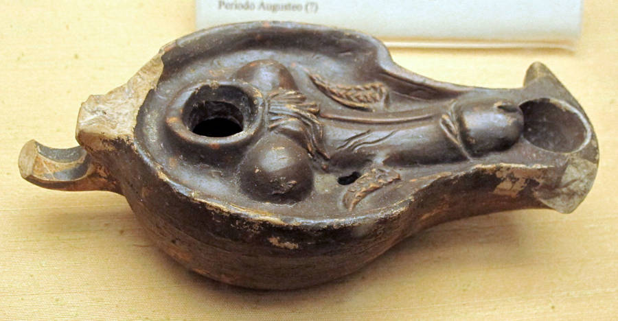 an ancient roman terra cotta lamp decorated with a winged phallus